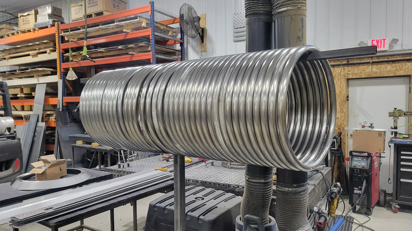 Long precision-rolled helical stainless steel burner coil mounted on a welding stand